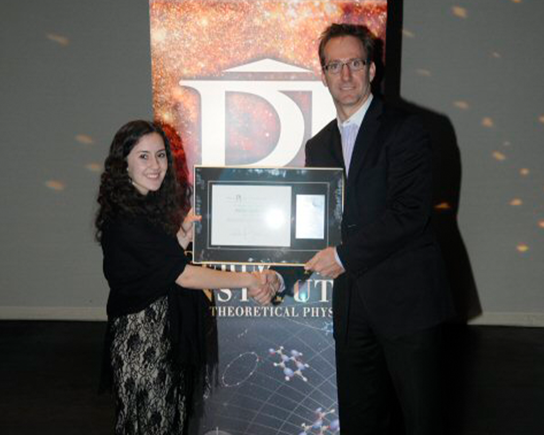 Paige Murphy, 2012 Luke Santi Memorial Award winner posing with her award and shaking the hand of Greg Dick, Perimeter Director of Educational Outreach,