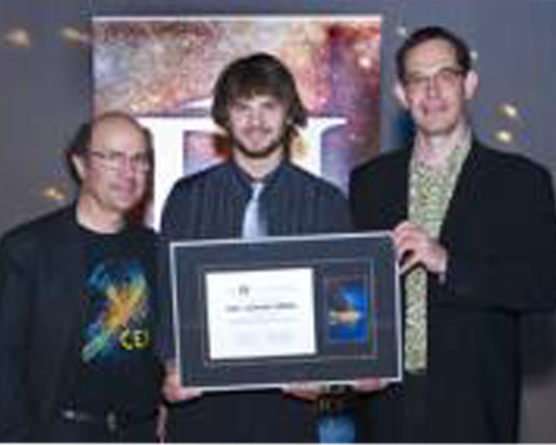 Luke Santi Memorial Award recipient Paul Brogee accepting the award from Nobel Laureate Frank Wilczek, and Director of PI Neil Turok.