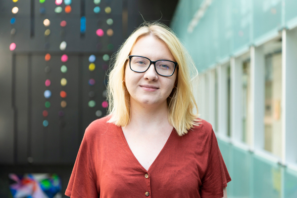 Portrait of a woman with blonde hair and a red shirt standing in the atrium