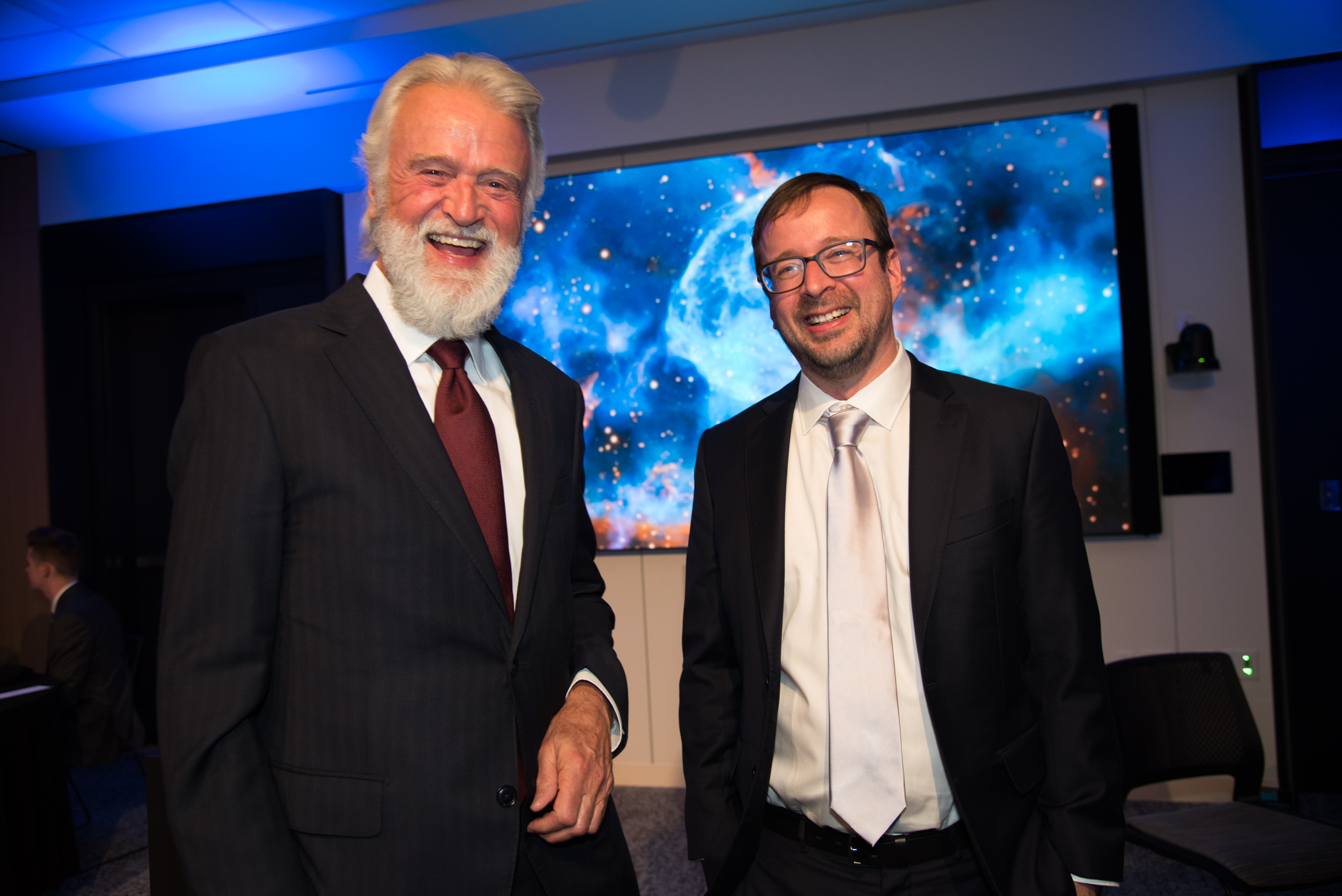 Two men standing together at an event smiling at the camera