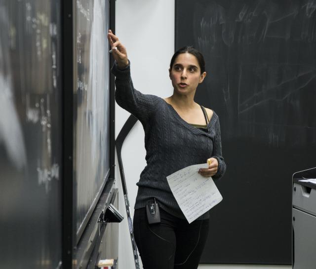 Woman teacher pointing to something on a blackboard