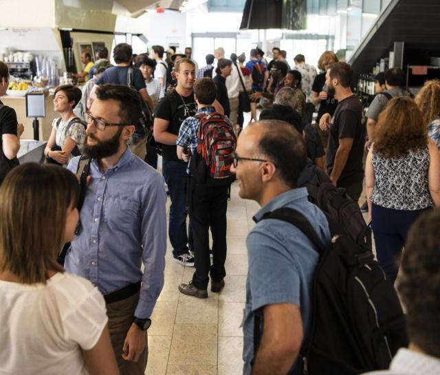 Crowd of people talking in groups in a building hallway