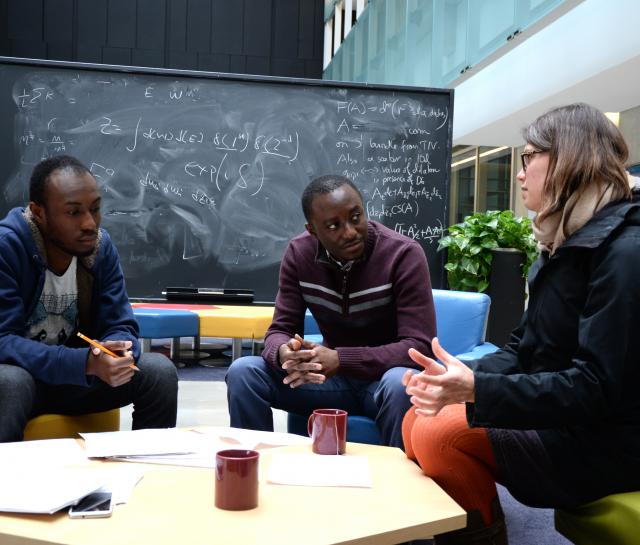 Two men and woman talking around a table in atrium