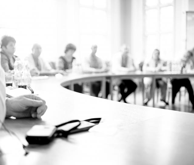 Black and white photo of people sitting around a curved table