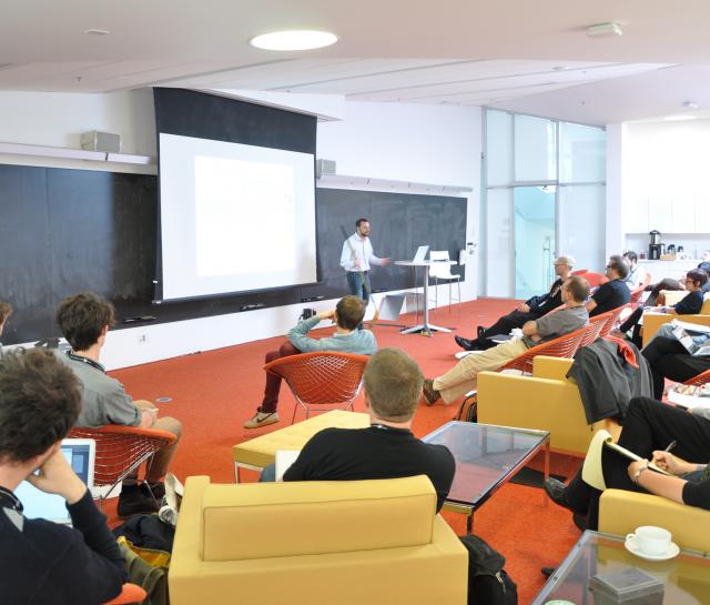 Man standing at the front of a lecture hall talking to people