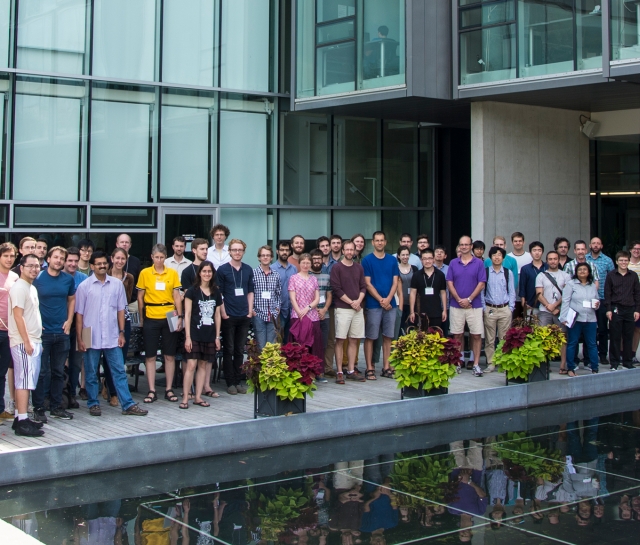 Group of people posing for group photo outside glass building