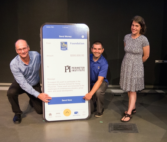 Two men kneeling beside an RBC sign and a woman standing beside