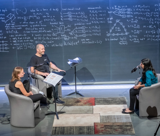 Three people sitting in a theatre recording a podcast together