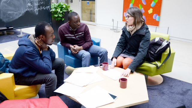 Two men and woman talking around a table in atrium