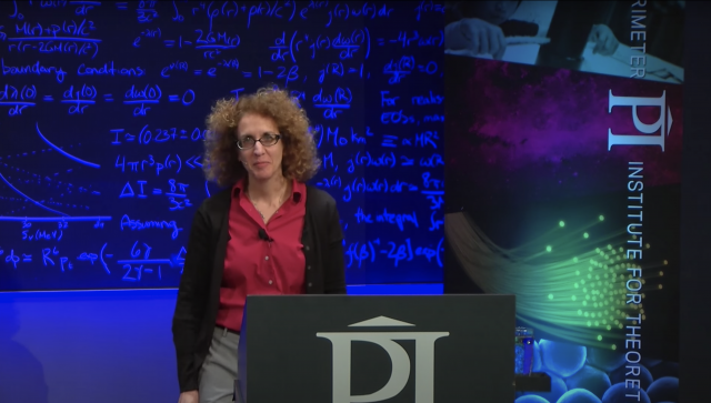 Woman standing in front of a lecture hall speaking to a group of people