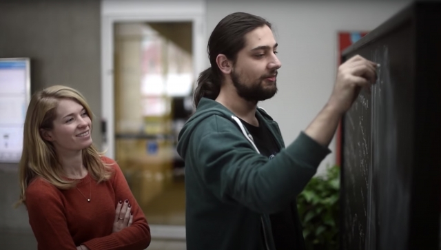 Man and woman standing at a chalkboard together working on a problem