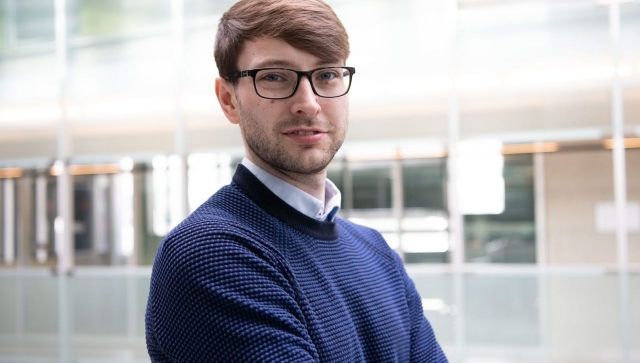 Portrait of Ciaran Gilligan Lee standing in an atrium