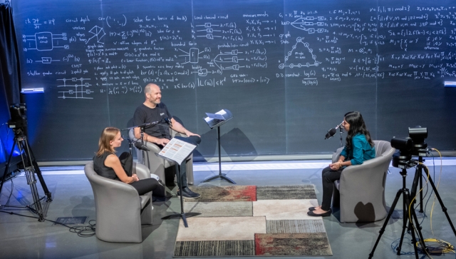 Three people sitting in a theatre recording a podcast together