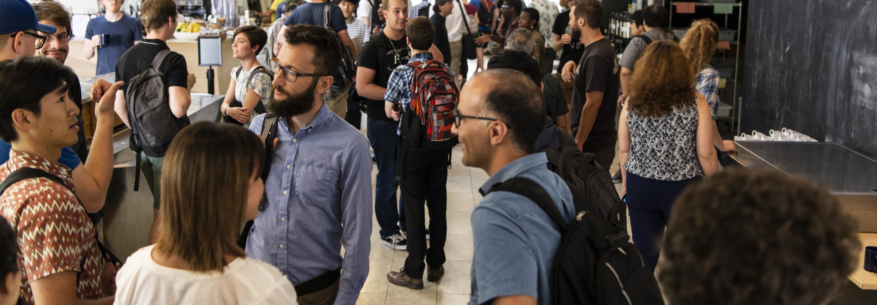 Crowd of people talking in groups in a building hallway