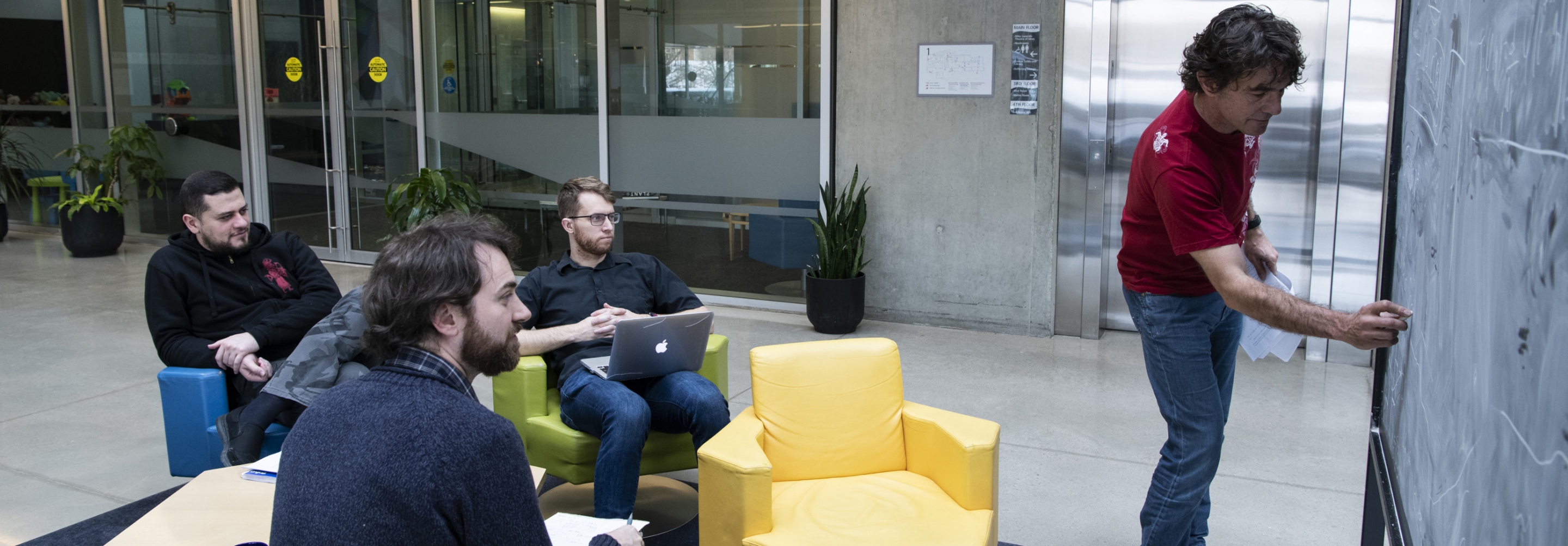 Man standing at blackboard teaching to 3 other men