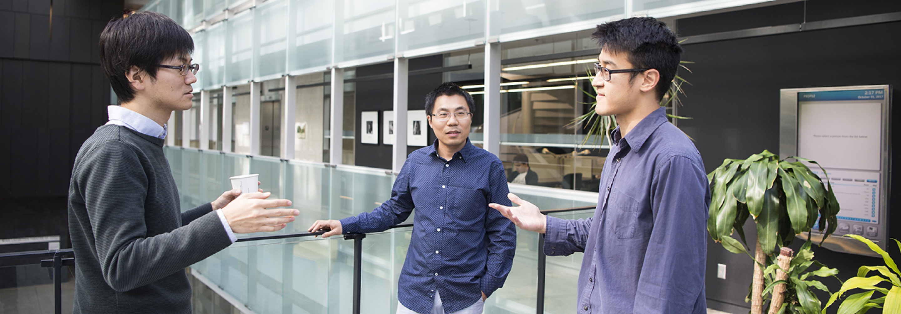 Three asian men standing in atrium talking