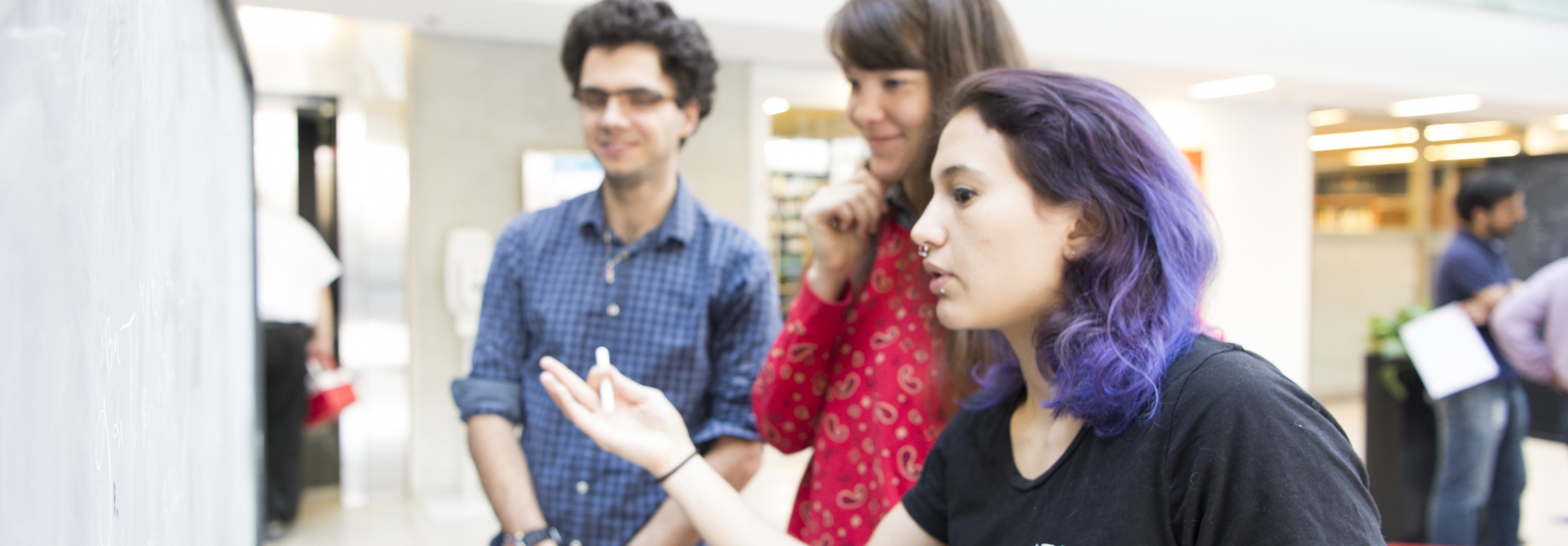 3 PSI students 2018 interacting if front of a blackboard in the atrium