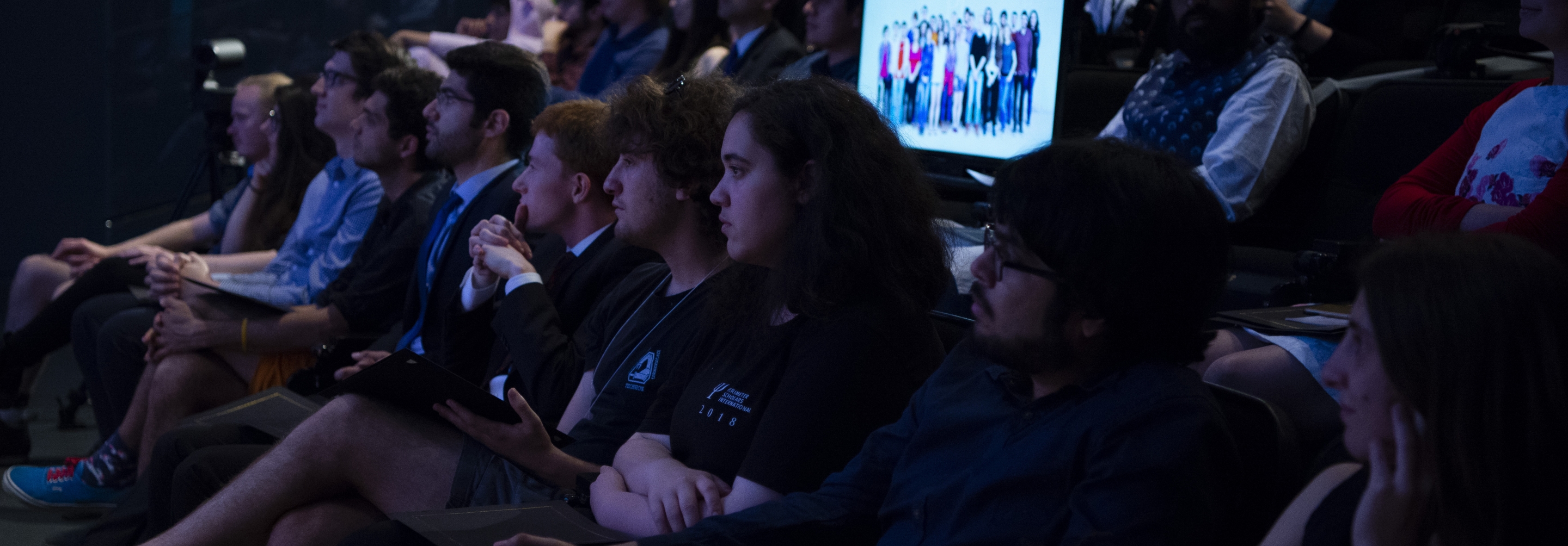 Group of students in a theatre listening to a presentation