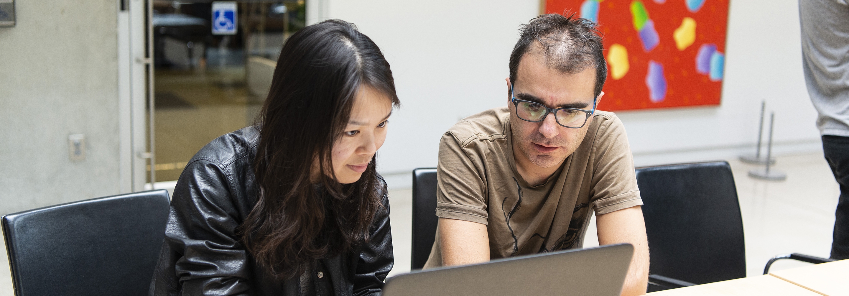 Man and women sitting at a table working on a computer together