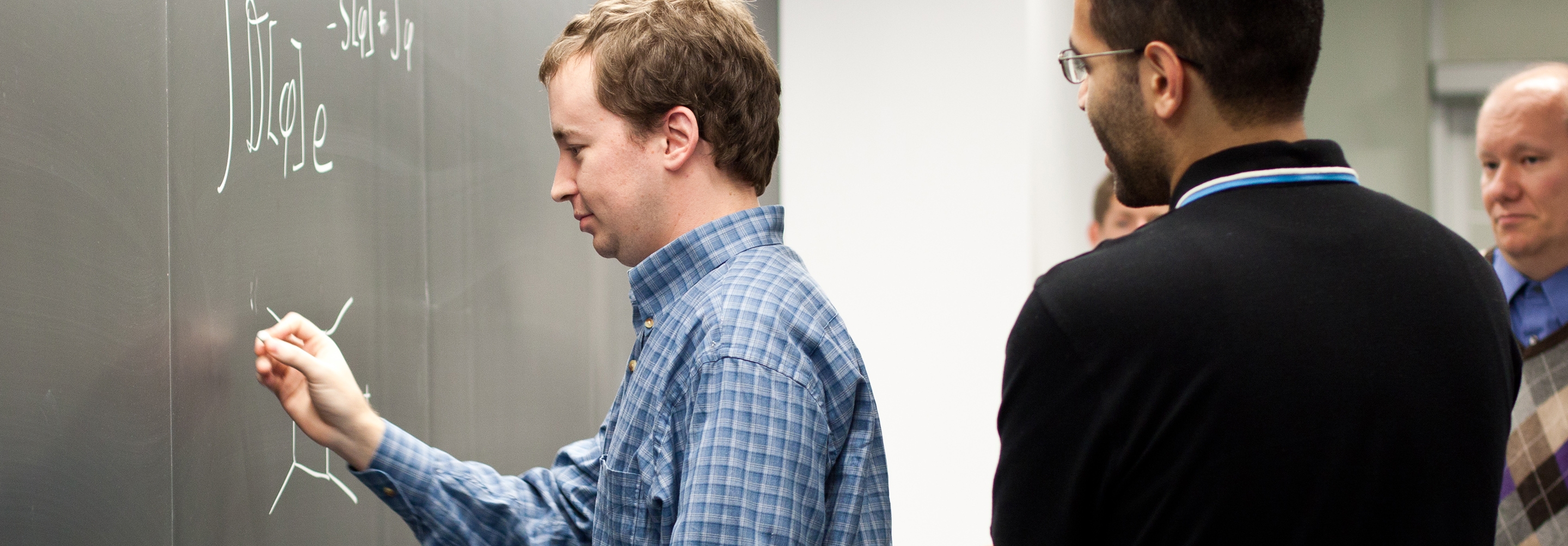 Man standing at blackboard teaching to 3 other men