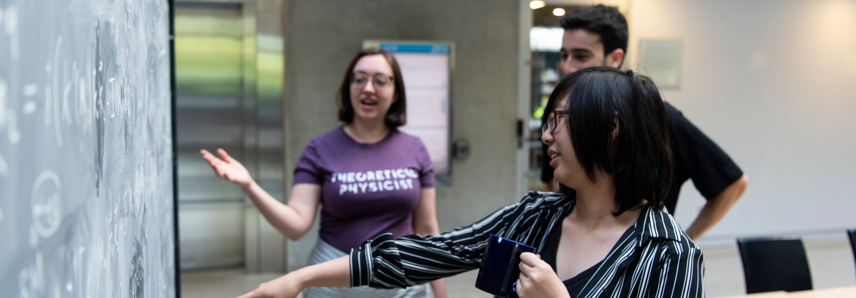 Three students collaborating together at a blackboard