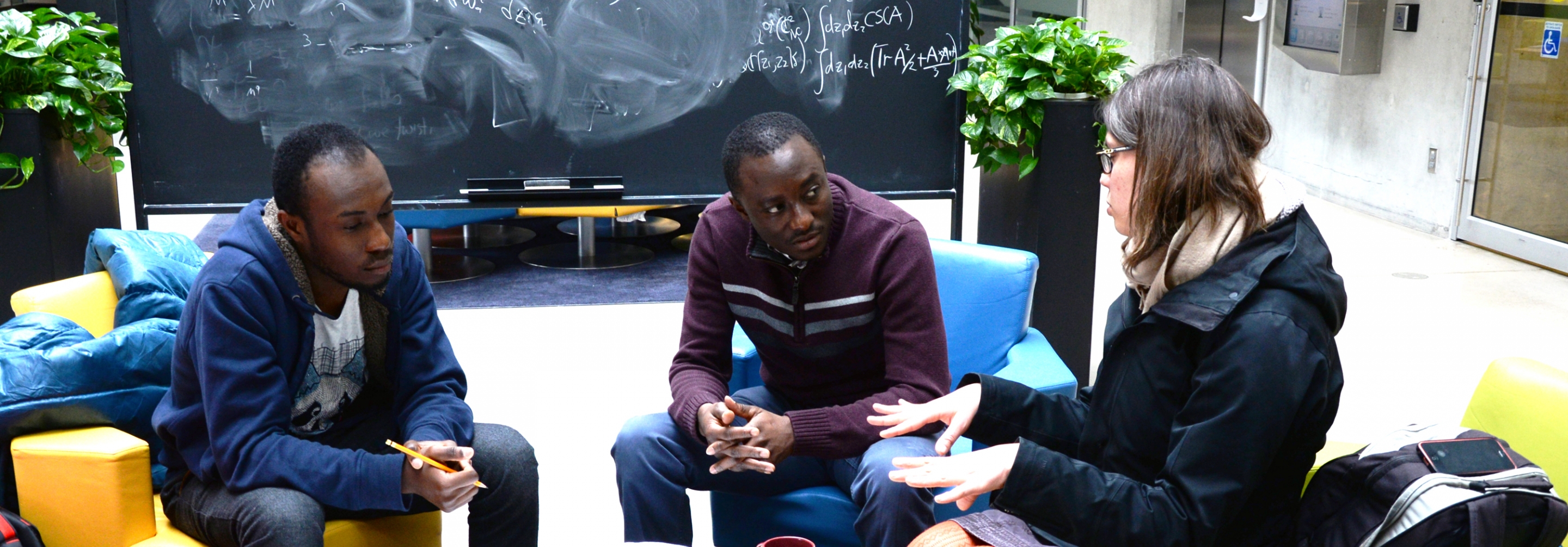 Two men and a women discussing physics together in an atrium