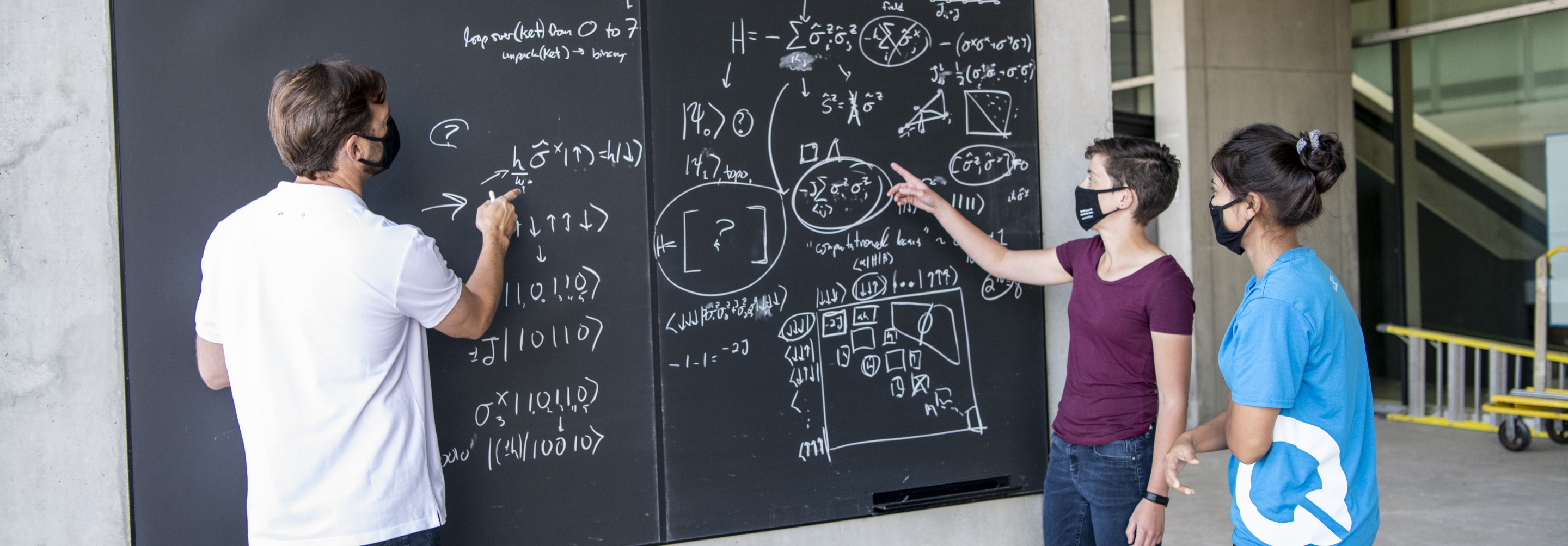 Man and two women working together on a blackboard outside