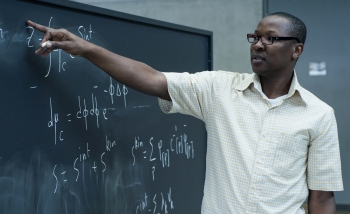 Dine Ousmane Samary, pointing at an equation on a blackboard in PI's atrium