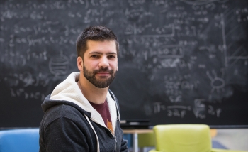 Portrait of Giacomo Torlai in front of a blackboard in PI's atrium