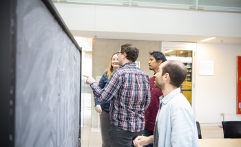 Bianca Dittrich, Aldo Riello, Etera Livine, and Christophe Goeller working at a blackboard