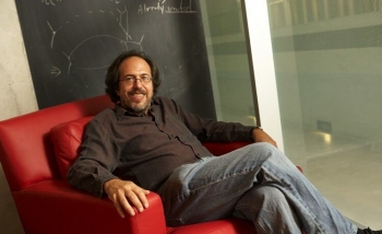 Man sitting on chair infront of chalkboard 