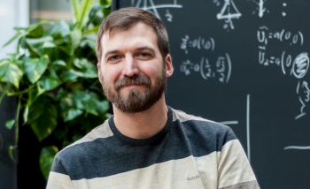 Man sitting on armchair in front of blackboard of equations