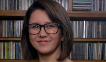 Portrait of a woman wearing a black shirt sitting in front of a bookshelf