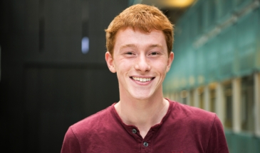 Portrait of a young man wearing a red shirt standing in an atrium