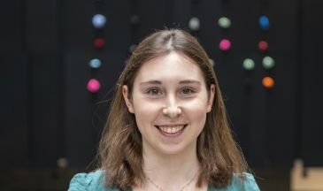 Portrait of a woman wearing a green shirt standing in an atrium