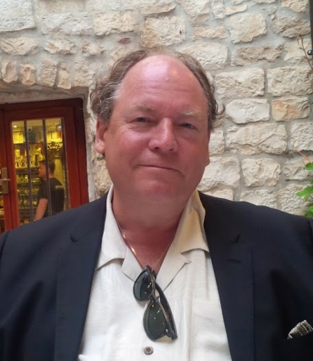 Portrait of a man in a suit sitting outside at a restaurant