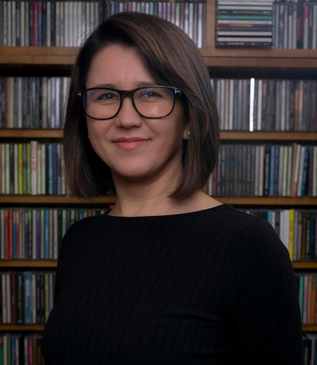 Portrait of a woman wearing a black shirt sitting in front of a bookshelf