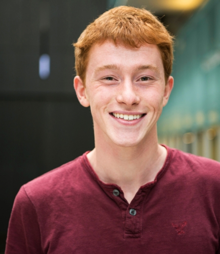 Portrait of a young man wearing a red shirt standing in an atrium