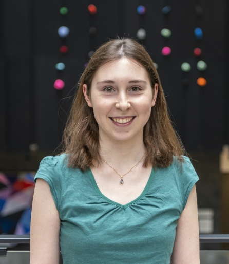 Portrait of a woman wearing a green shirt standing in an atrium